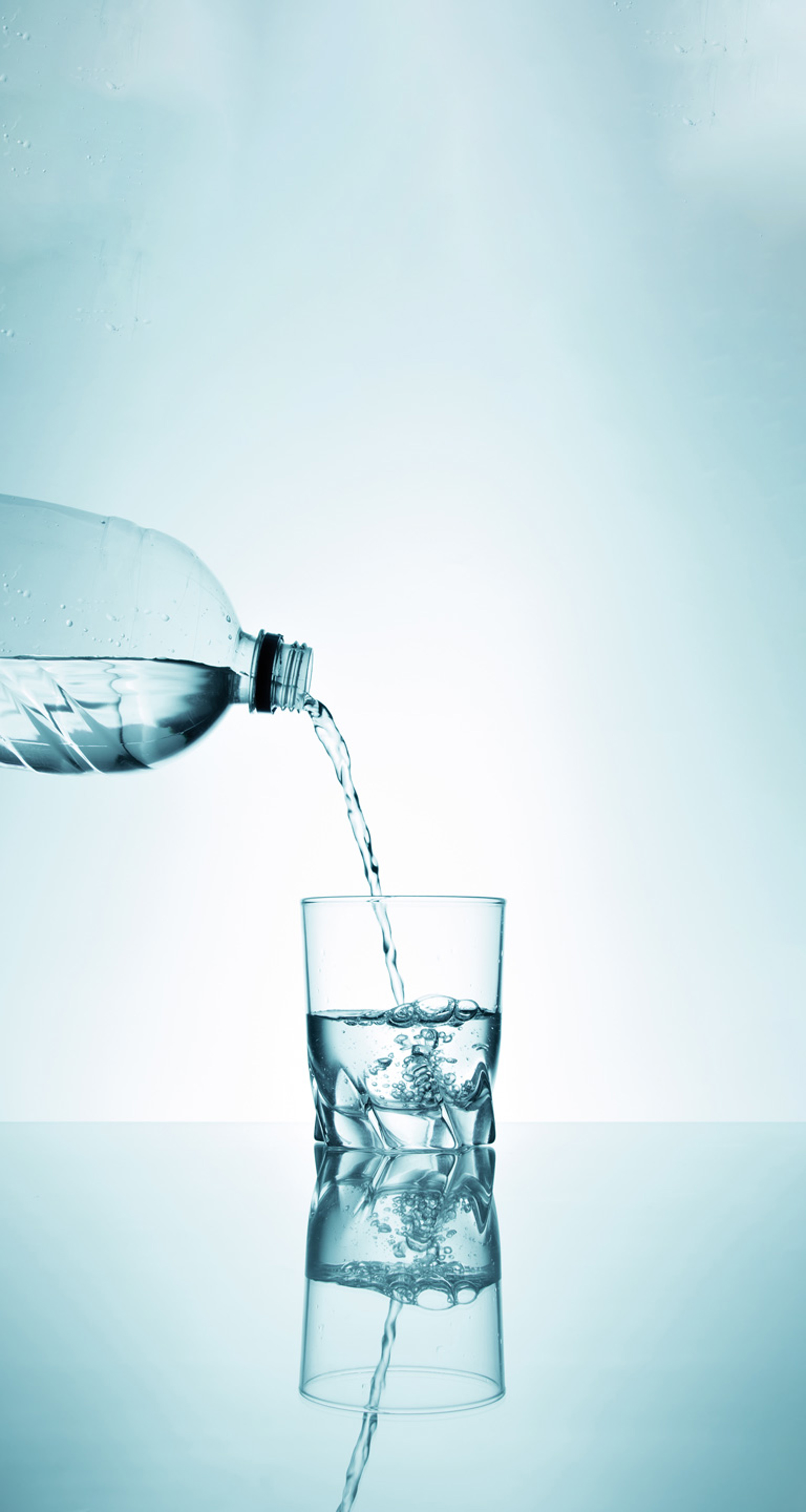 Wasser wird aus einer Plastikflasche in ein Glas gegossen