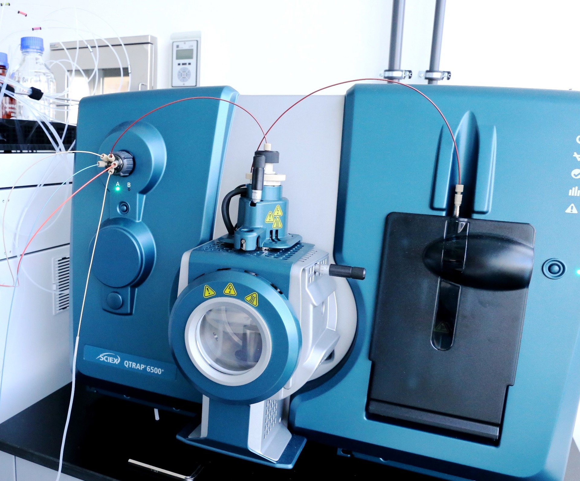 Blau-graues Massenspektrometer mit angeschlossenen Kabeln und Schläuchen in einem Labor